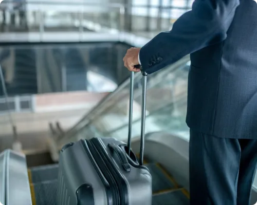 A chauffeur is about to hop on the escalator with a client's luggage at Milford Municipal airport