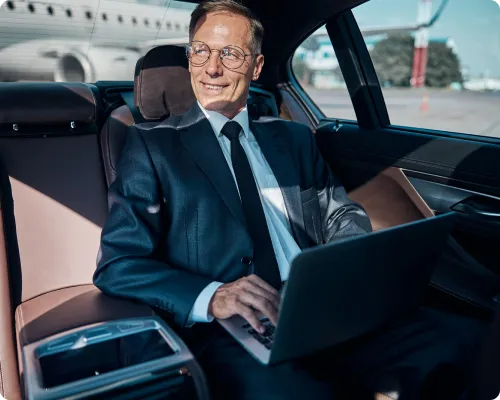 A business executive is happily working on his laptop while sitting in NYC United corporate limo at Logan airport