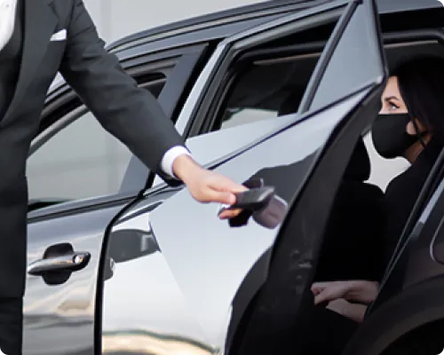 An NYC Brooklyn limo chauffeur is helping a client to get out of the vehicle after their trip from New York to Brooklyn