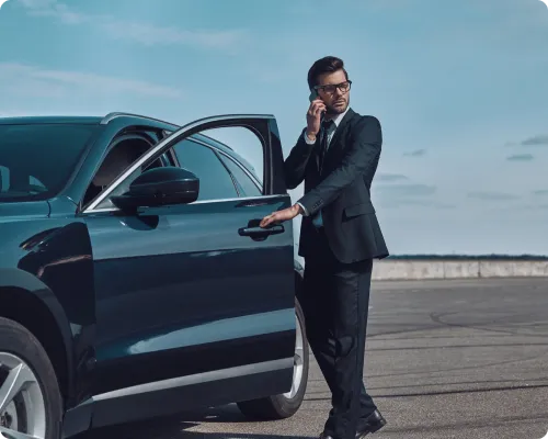 A uniformed chauffeur opening the door of a luxury black vehicle