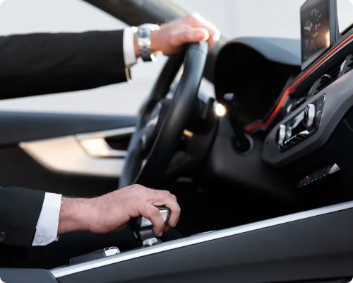 A side view of a uniformed chauffeur driving a limo