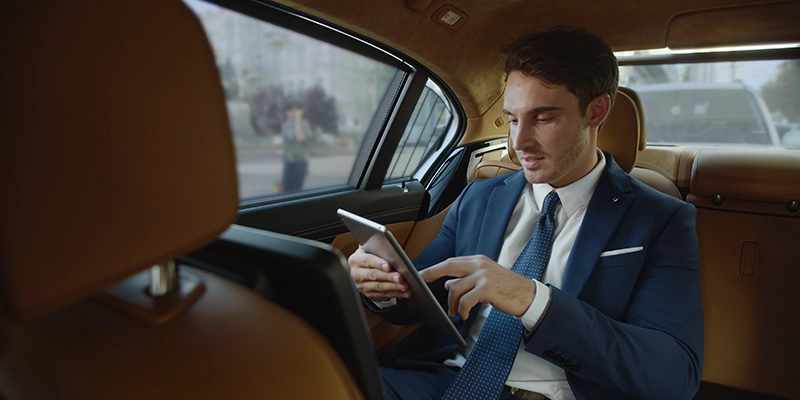 smiling male professional reading good news tablet computer automobile