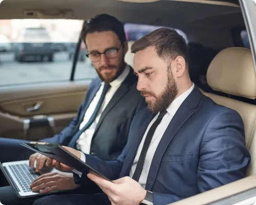 Two business travelers are having a meeting while commuting in a limo