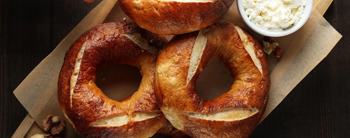 An image of freshly baked bagels on a tray with a side of cream cheese, promoting pre-flight meal options.