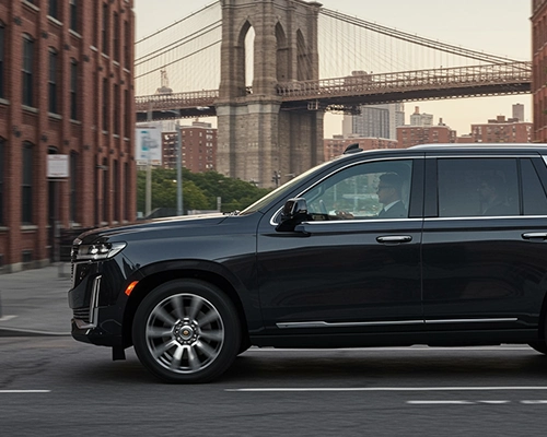A black luxury SUV on a street with the Brooklyn Bridge in the background.