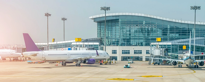 An image of an airport tarmac with airplanes and a terminal building, representing JFK & LaGuardia Airport. The scene highlights seamless airport transfers, promoting a safe and comfortable journey for kids with child safety seat options to or from NYC's major airports.