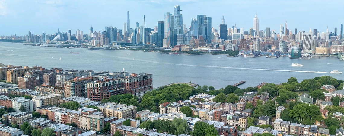 Hoboken Car Service for Waterfront Attractions: Stunning panoramic view of Hoboken, NJ, skyline across Hudson River with NYC towers, lush green parks, and historic buildings.