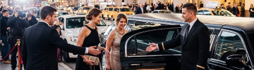 JFK Limo service for red carpet events: a glamorous couple arriving in a luxury black stretch limousine with limo service to JFK, stepping onto the carpet with flashing cameras and VIP treatment.