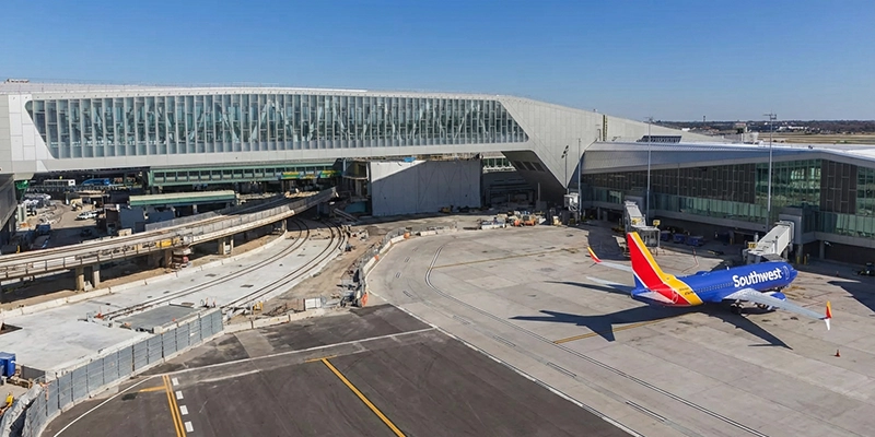 LaGuardia Airport (LGA): The newly transformed Terminal B featuring soaring floor-to-ceiling windows and a dual pedestrian skybridge over an active taxiway.