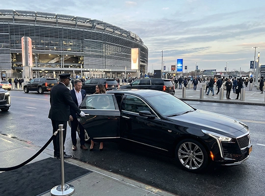 A black Cadillac limousine drops off VIPs at MetLife Stadium entrance under cloudy skies, with crowds arriving for FIFA World Cup 2026. Scene highlights premium arrivals ahead of the 2026 FIFA World Cup.