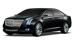 Tilted front and side view of sleek black Cadillac XTS under NYC United limo.