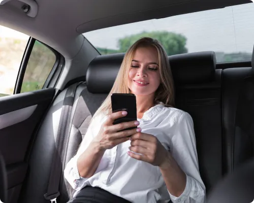 A passenger is enjoying her limo trip in East Hampton while using her phone.